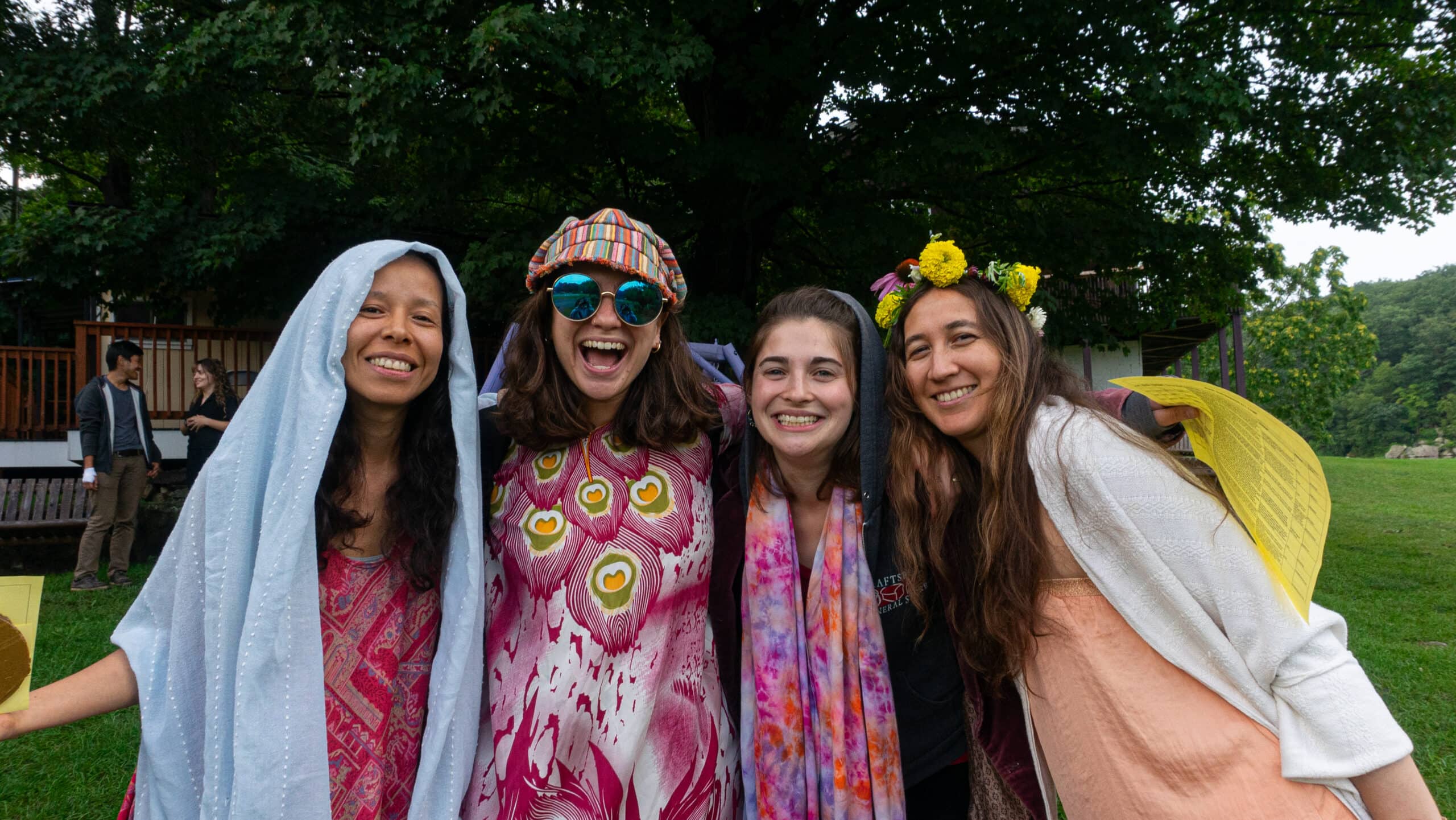 Four individuals smiling together in colorful costumes outdoors.