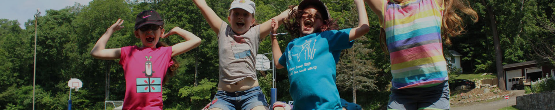 Group of children joyfully jumping outdoors in bright summer clothing.